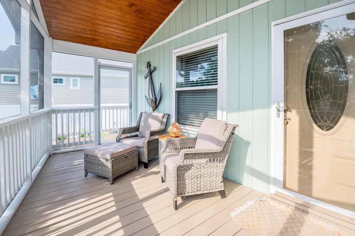 A serene interior scene featuring woven chairs and a small coffee table, with a decorative lamp and anchor decor. The setting is intimate and inviting, ideal for enjoying morning coffee, relaxing, or socializing. The calm, welcoming mood evokes a tranquil retreat connected to the outdoors.