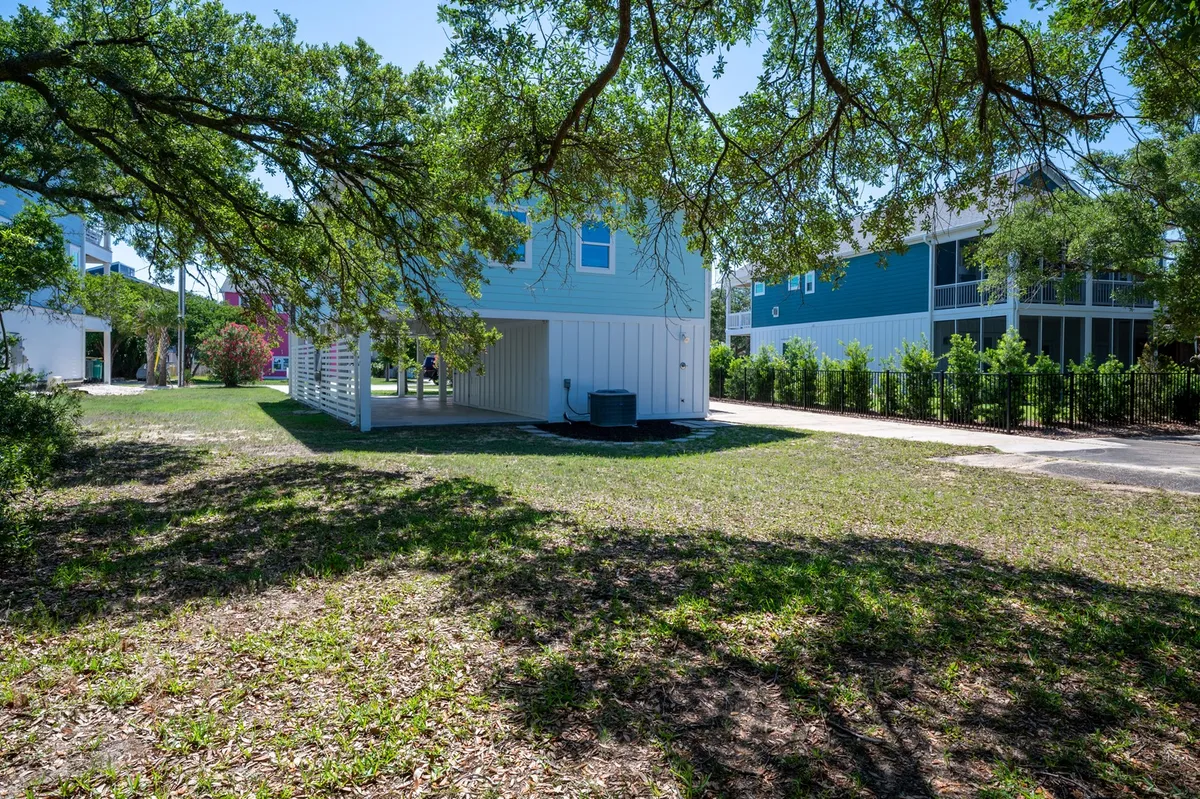A cheerful neighborhood scene featuring colorful houses, a large shade-providing tree, and an open lawn where children play and families gather. The image conveys a friendly, communal atmosphere and emphasizes the family-friendly character of the street.