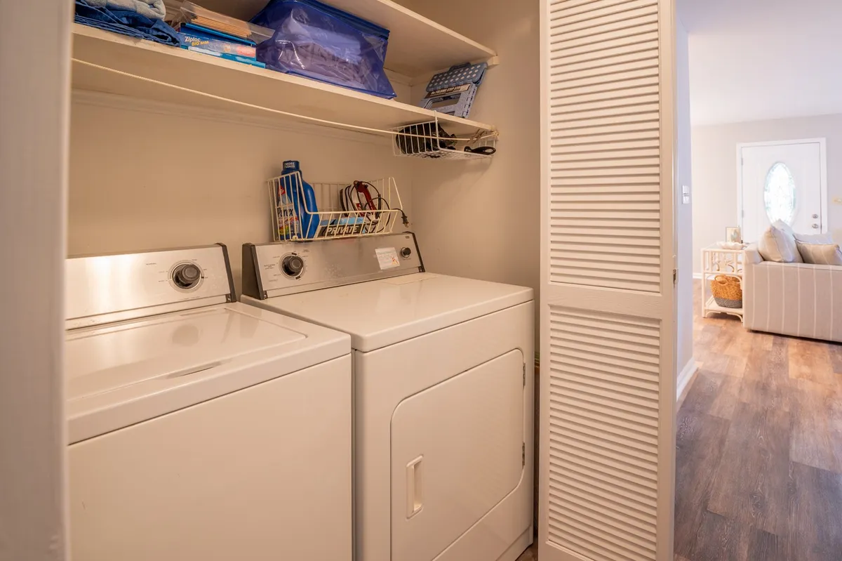 A practical laundry room with a washer, dryer, shelves neatly organized with supplies, and laundry baskets. The space is bright and efficient, emphasizing the convenience of in-home amenities.