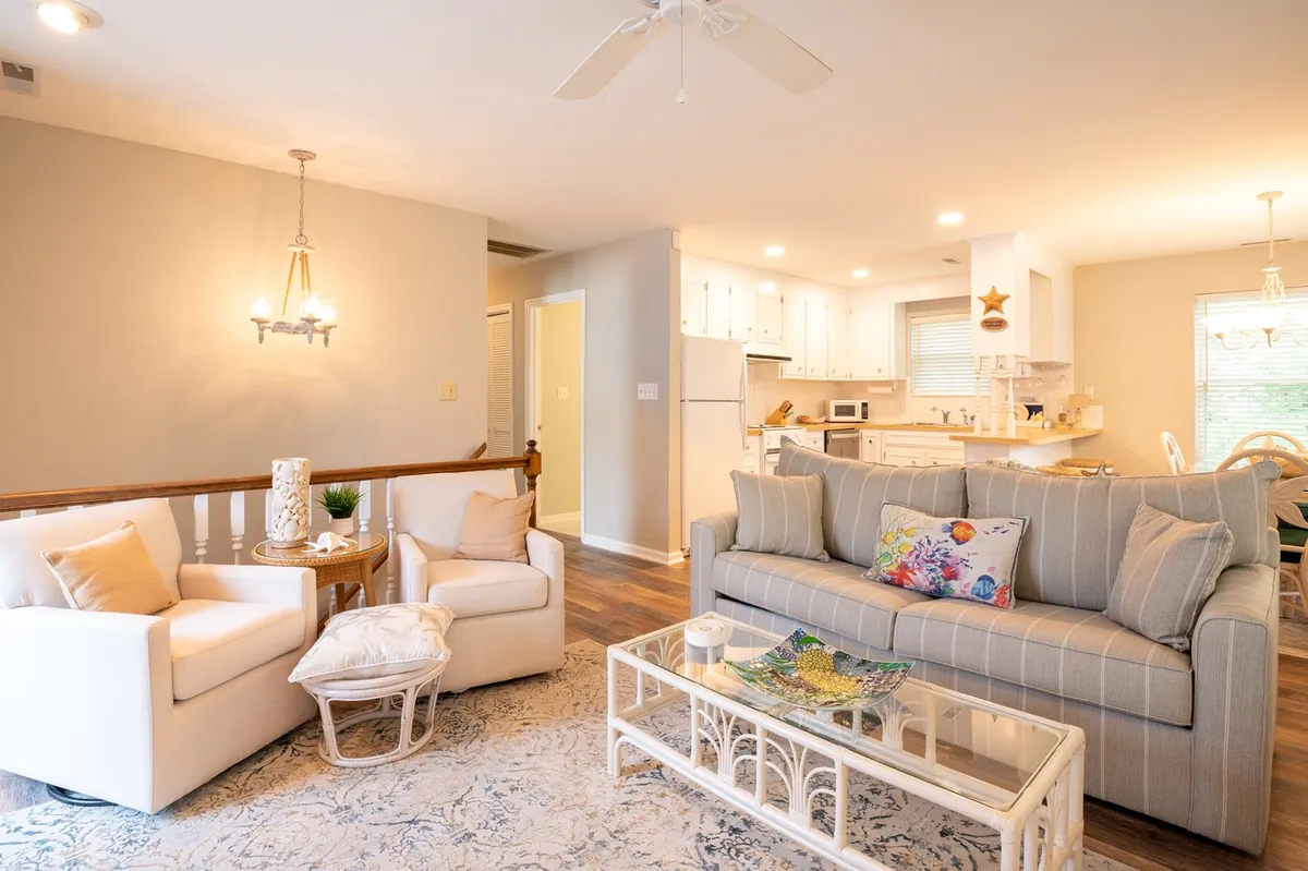 A cozy living area with a sofa, armchairs, and a coffee table, illuminated by a contemporary light fixture. The arrangement suggests a comfortable space for socializing or relaxing after a day out. The muted palette and soft textures create a restful retreat.