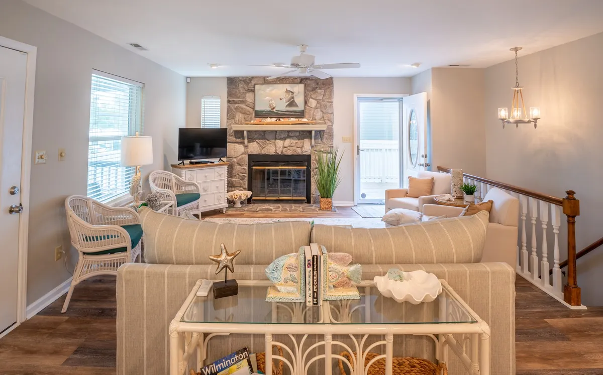 A comfortable living room featuring a fireplace, sofa, coffee table, smart TV, and a sliding door that opens to the balcony, letting in abundant natural light and fresh air. The room is arranged to encourage both relaxation and social gathering.